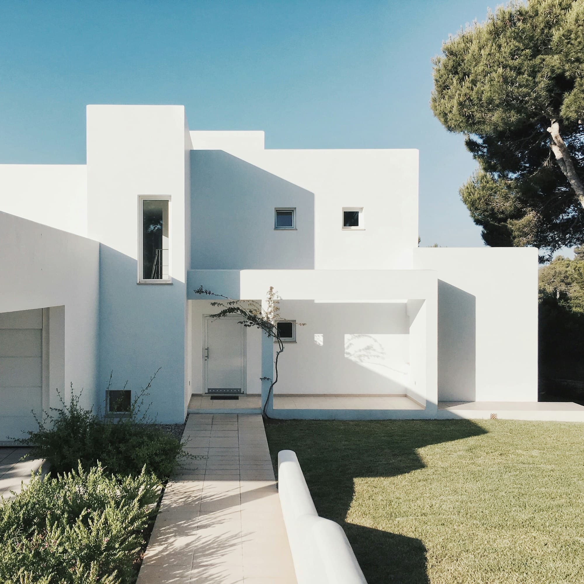 Maison minimaliste en béton blanc entourée de verdure